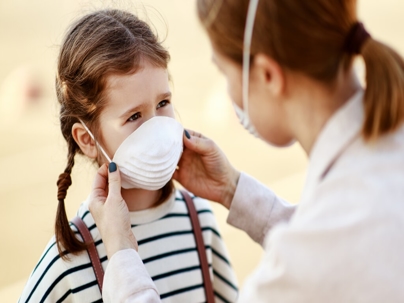 Mother putting on medical mask on daughter