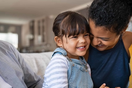Mom and daughter hugging and smiling in family room